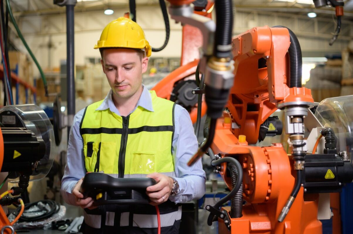 A male worker is controlling a welding robot.